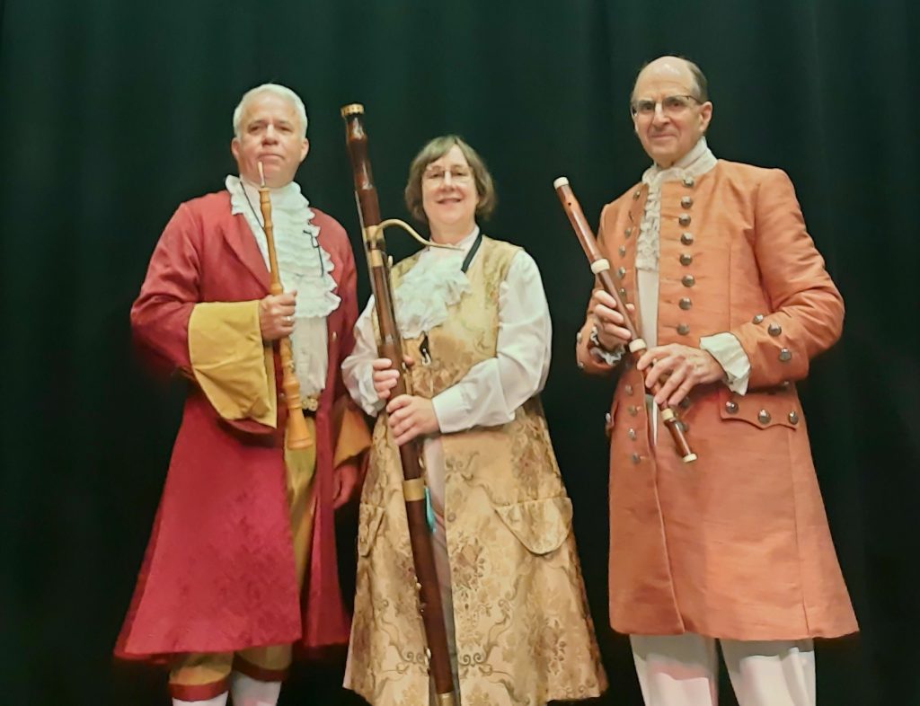 two men and a woman in Baroque costume with a flute, bassoon and oboe